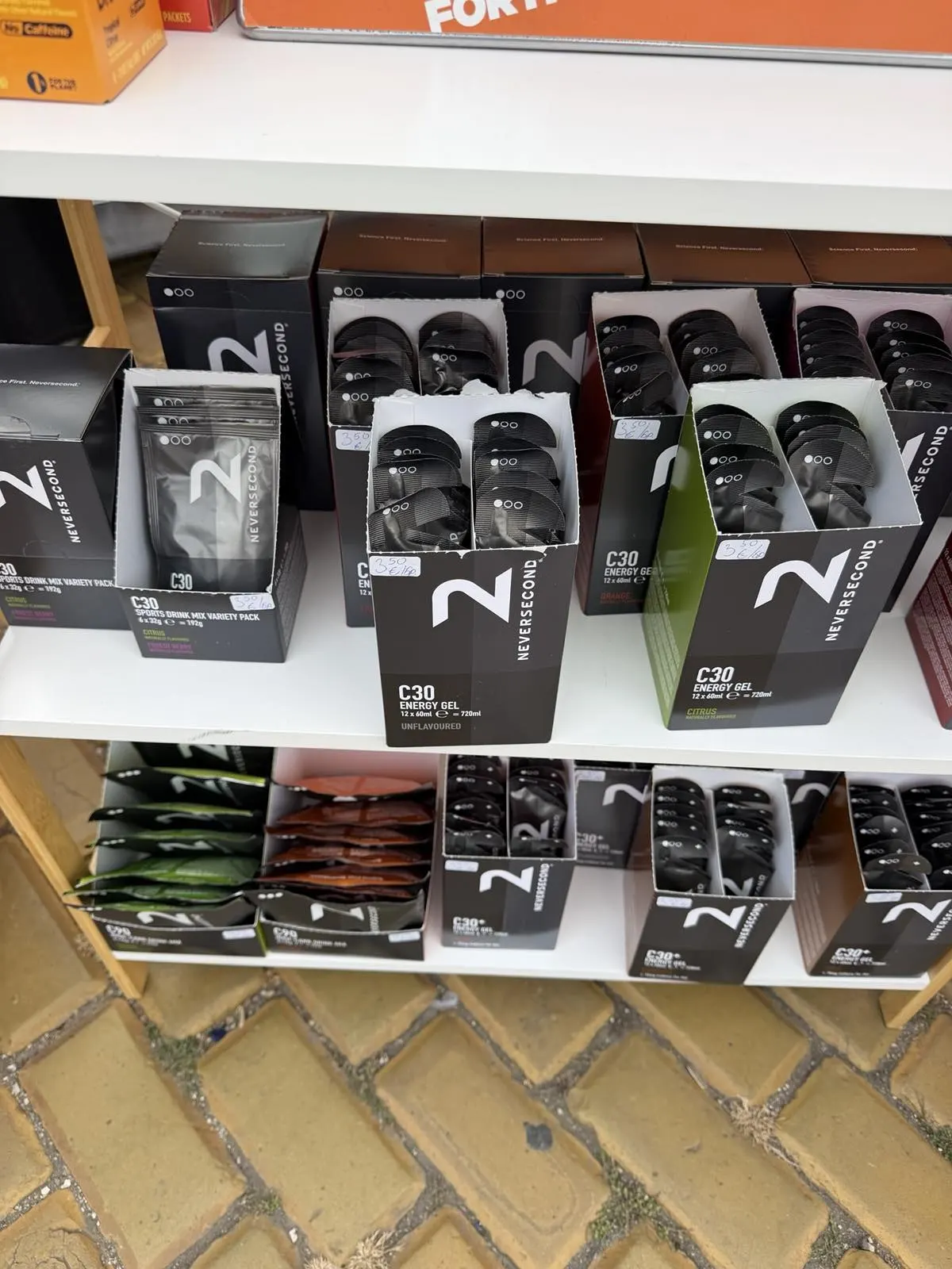 Neversecond C30 energy gels and drink mixes arranged on wooden shelves at the expo tent