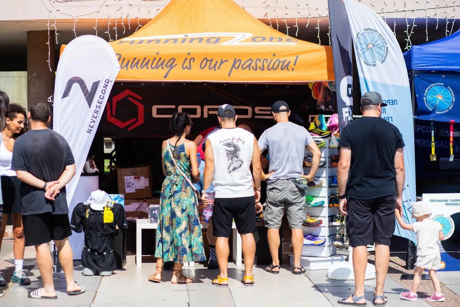 Running Zone expo tent at Tryavna Ultra with COROS and Neversecond branding, visitors at the counter seen from behind